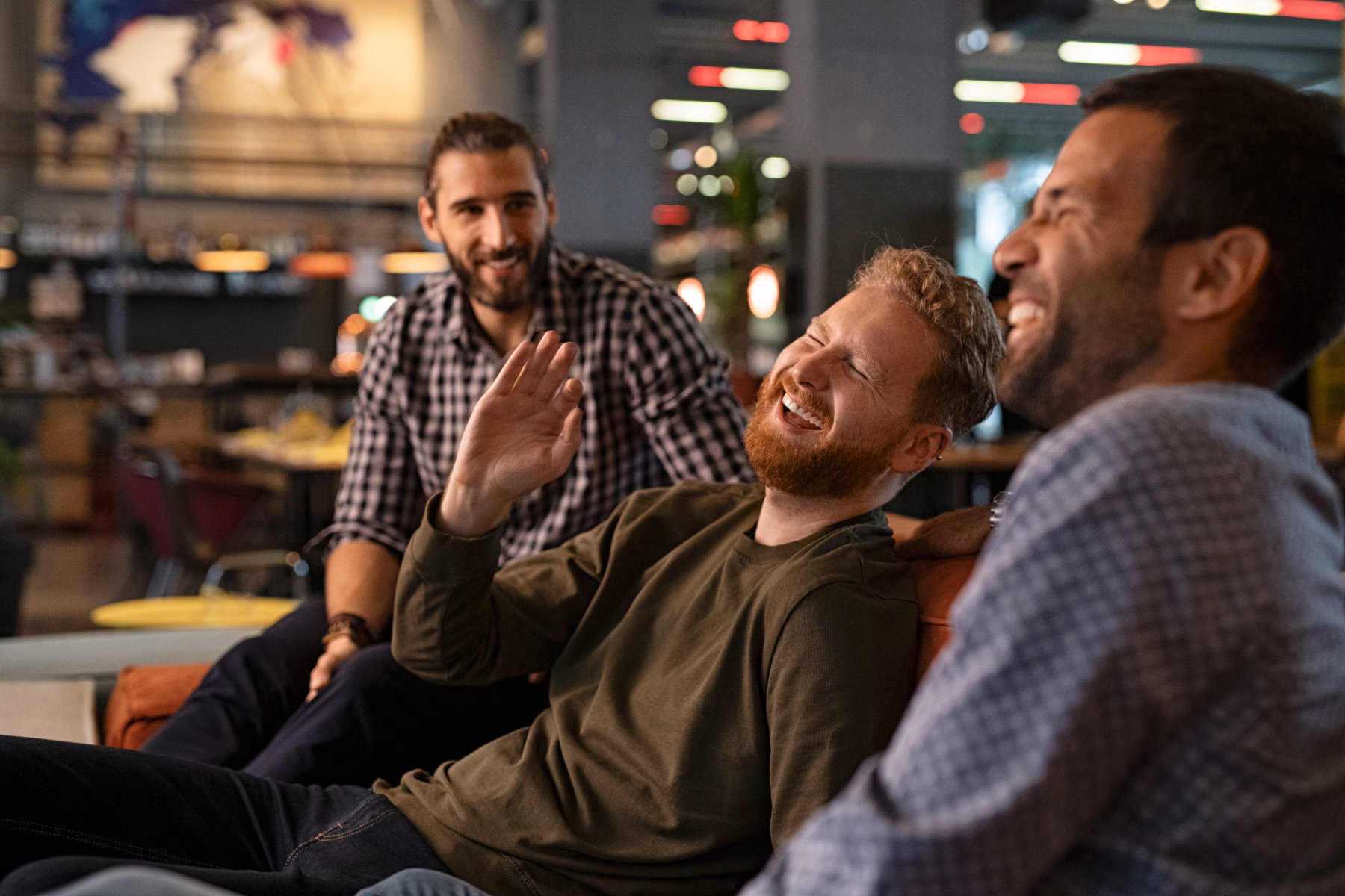 A group of men sat on a sofa laughing together