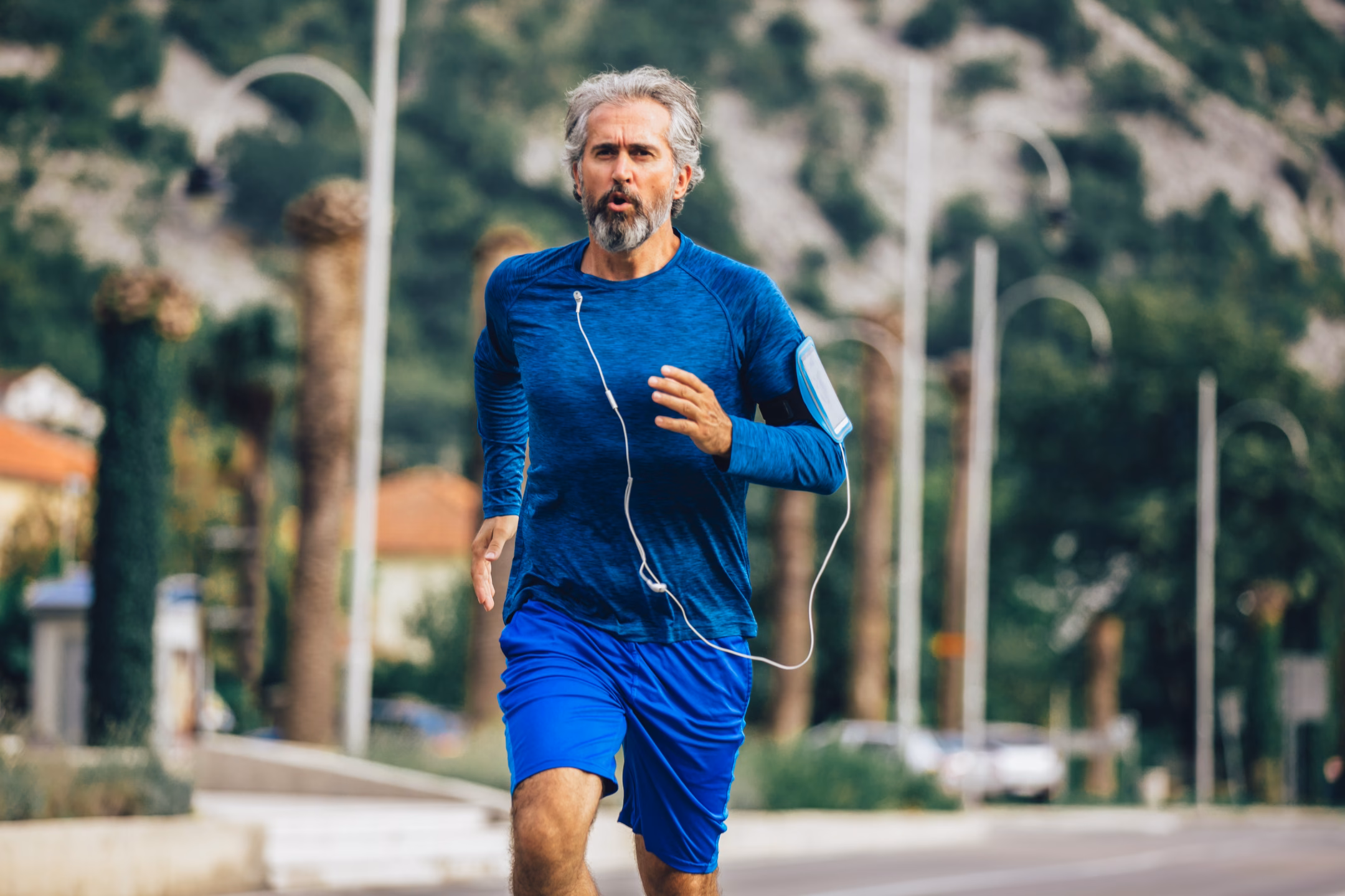 older man running down a street with earphones in