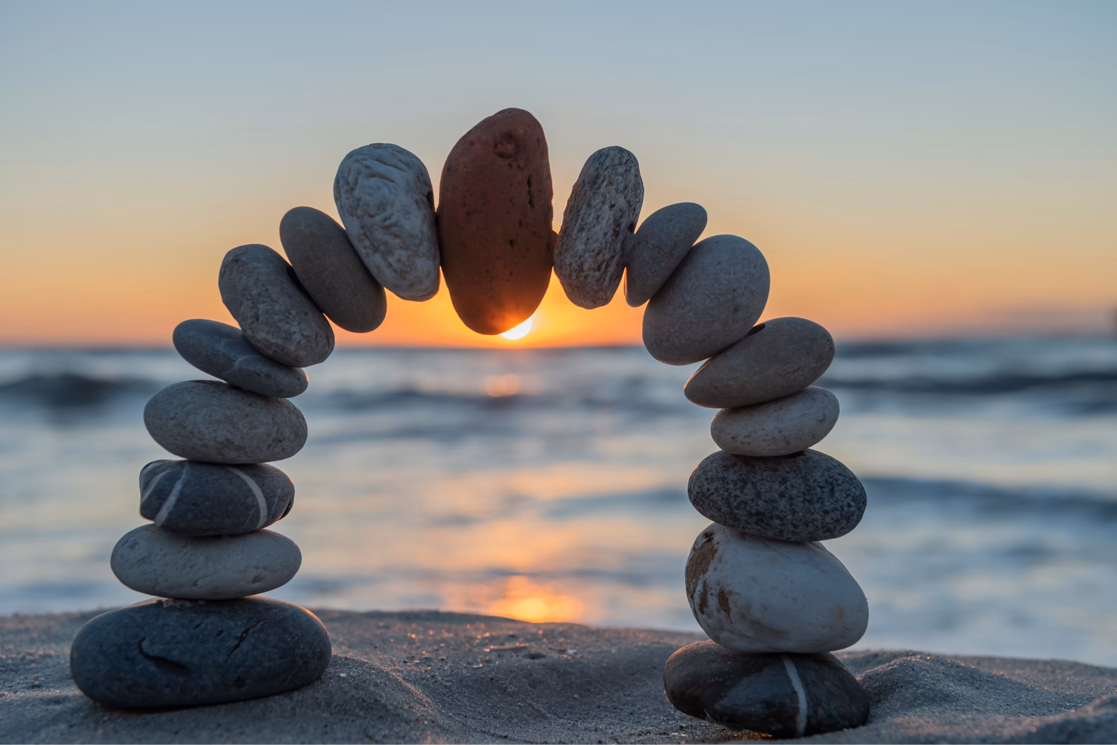 Pebble display on a beach, with a sunset in the background